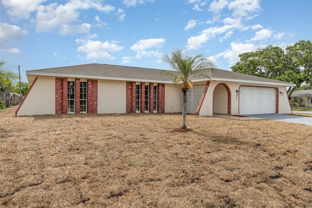 ranch-style house featuring concrete driveway, a front lawn, stucco siding, and a garage