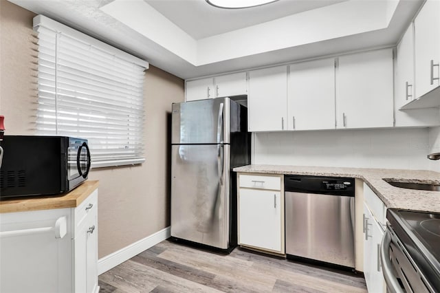 516 Polaris Loop Unit 110, Casselberry, FL 32707 - kitchen with baseboards, white cabinets, stainless steel appliances, and light wood-type flooring