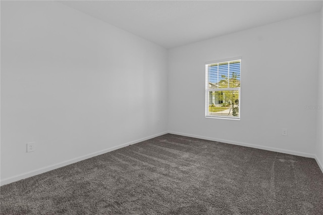 empty room with dark carpet and baseboards