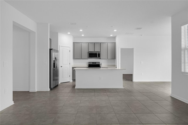 kitchen with tile patterned floors, an island with sink, gray cabinets, appliances with stainless steel finishes, and recessed lighting