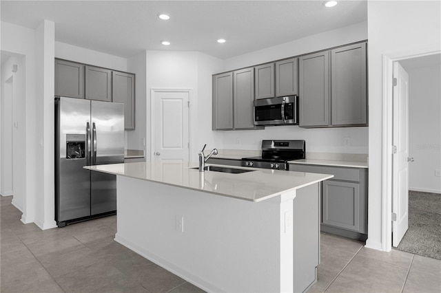 kitchen with gray cabinets, appliances with stainless steel finishes, a sink, and a kitchen island with sink