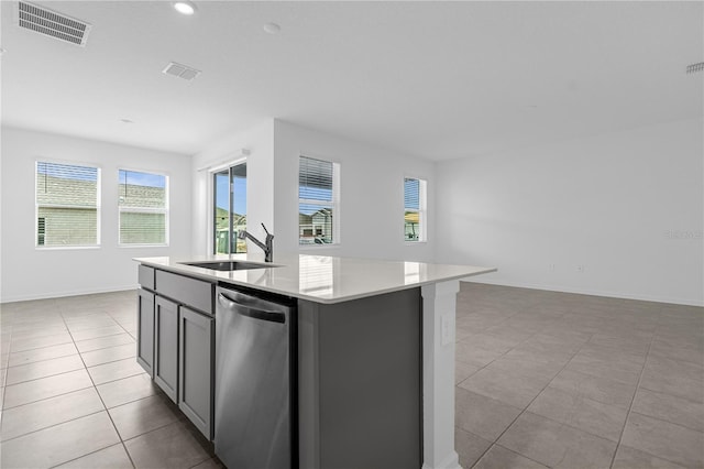 kitchen featuring stainless steel dishwasher, a sink, a center island with sink, visible vents, and light countertops