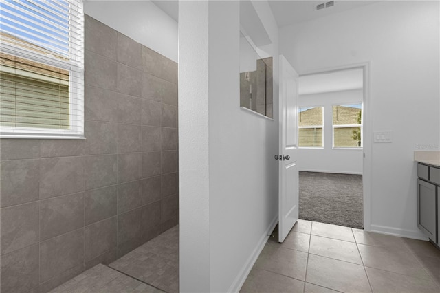 full bath with vanity, baseboards, tile patterned flooring, and a walk in shower