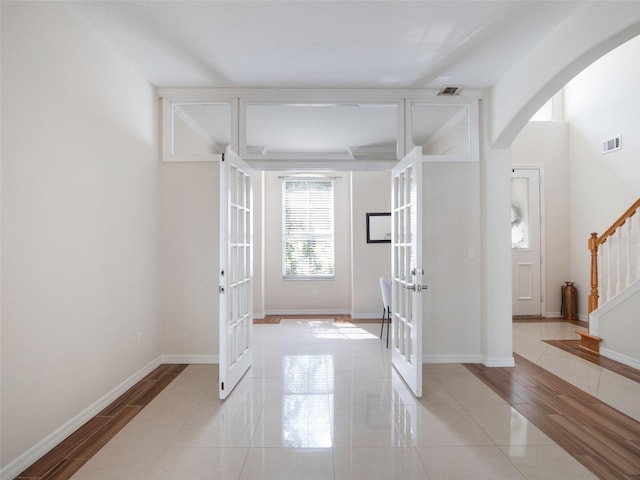 tiled entryway with stairway, arched walkways, french doors, and visible vents