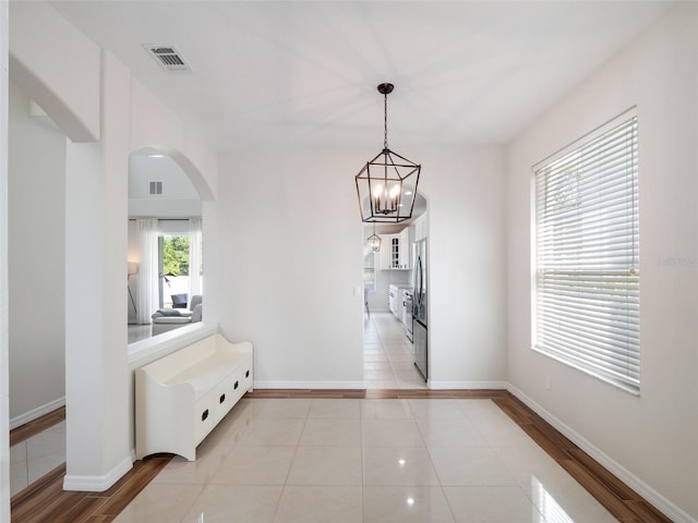 hall featuring baseboards, visible vents, arched walkways, and light tile patterned floors