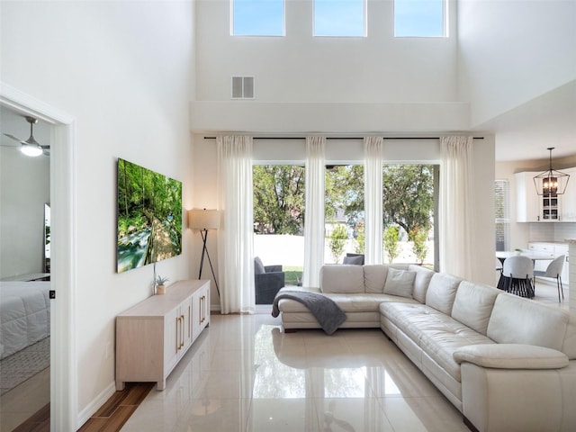 living area with a ceiling fan, a high ceiling, a healthy amount of sunlight, and visible vents