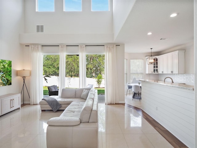 living room with a wealth of natural light, visible vents, a high ceiling, and light tile patterned floors