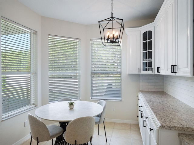 dining space featuring baseboards, a notable chandelier, and light tile patterned floors
