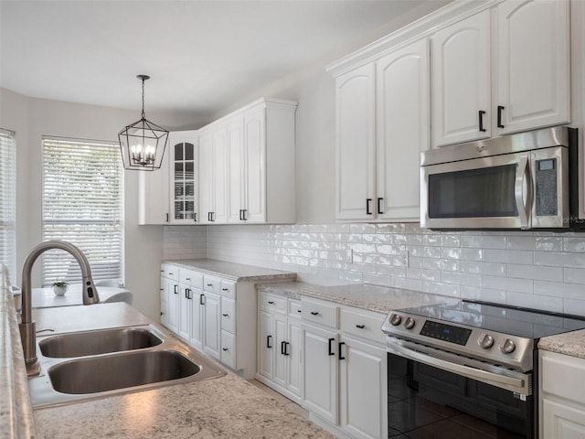 kitchen with an inviting chandelier, a sink, decorative light fixtures, appliances with stainless steel finishes, and white cabinetry