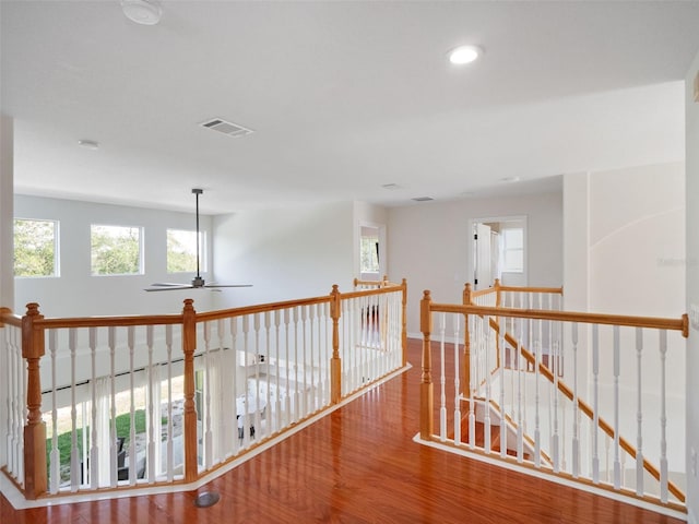 corridor featuring plenty of natural light, wood finished floors, visible vents, and an upstairs landing
