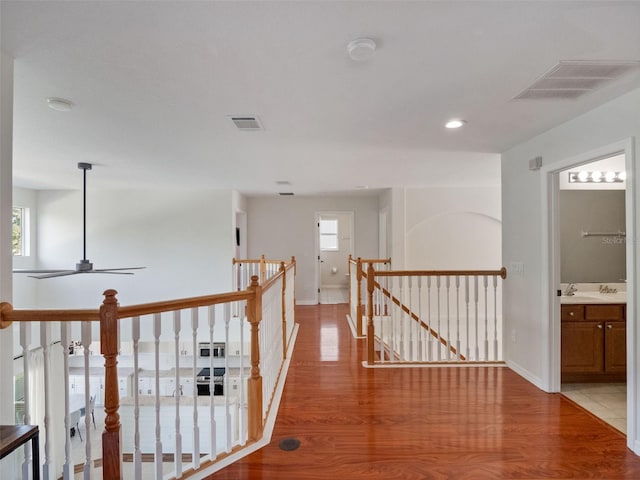 corridor featuring visible vents, light wood finished floors, and an upstairs landing