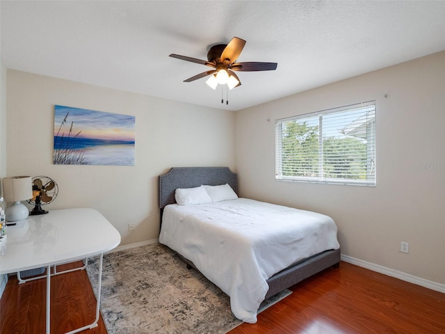bedroom with wood finished floors, baseboards, and a ceiling fan
