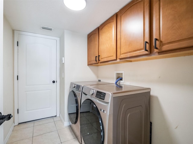 laundry room with light tile patterned flooring, washing machine and dryer, baseboards, visible vents, and cabinet space
