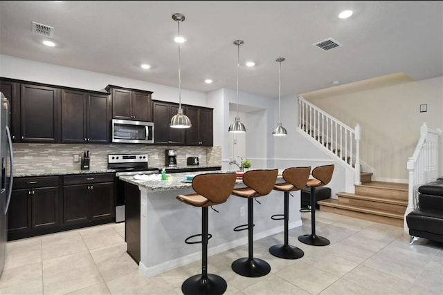 3806 Lana Ave, Davenport, FL 33897 - kitchen with appliances with stainless steel finishes, a kitchen breakfast bar, tasteful backsplash, light stone counters, and a center island with sink
