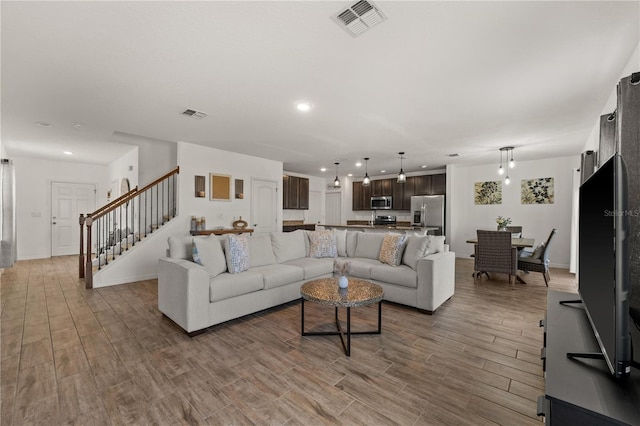 living room featuring stairs, recessed lighting, visible vents, and wood finished floors