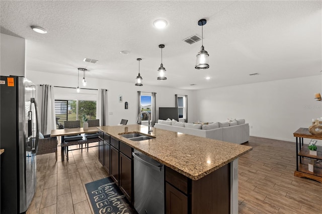 kitchen with dark brown cabinetry, visible vents, light wood-type flooring, a sink, and stainless steel appliances