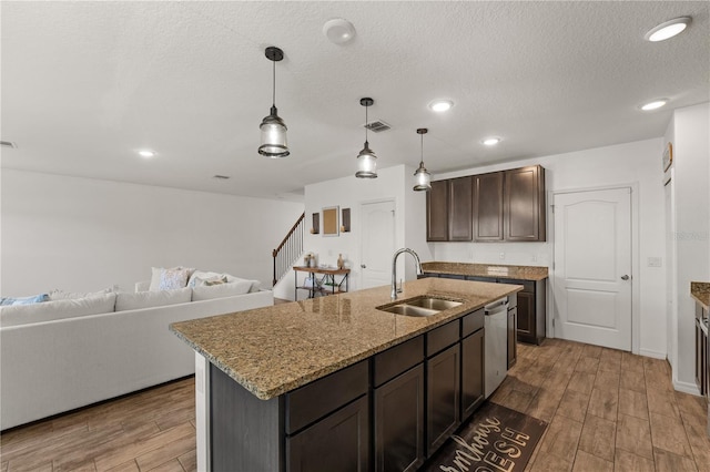 kitchen with dark brown cabinetry, a sink, wood finished floors, stainless steel dishwasher, and visible vents