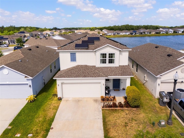 traditional-style home featuring a residential view, roof with shingles, a front yard, solar panels, and driveway