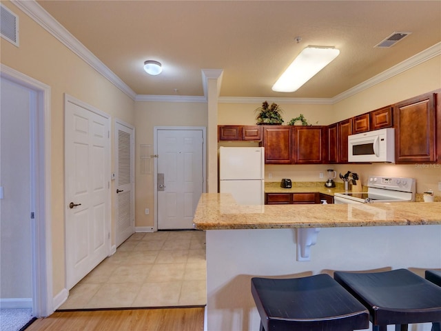 kitchen featuring visible vents, crown molding, a peninsula, and white appliances