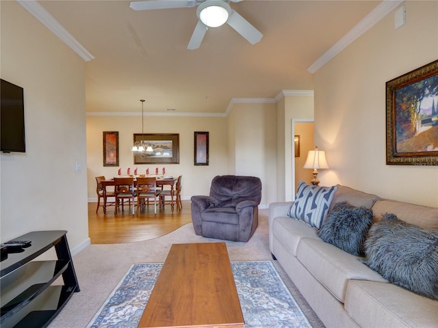 living room featuring baseboards, ornamental molding, carpet, and ceiling fan with notable chandelier