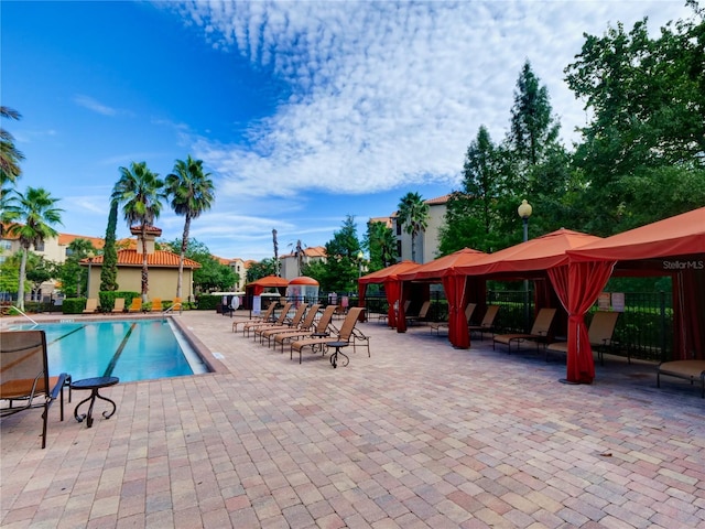 community pool featuring fence, a gazebo, and a patio area