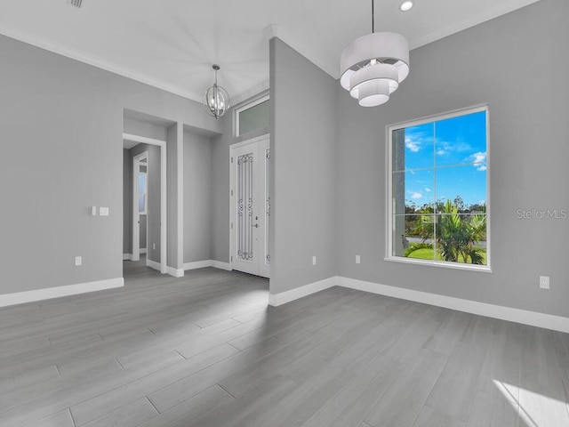 unfurnished room with wood finished floors, baseboards, an inviting chandelier, and ornamental molding