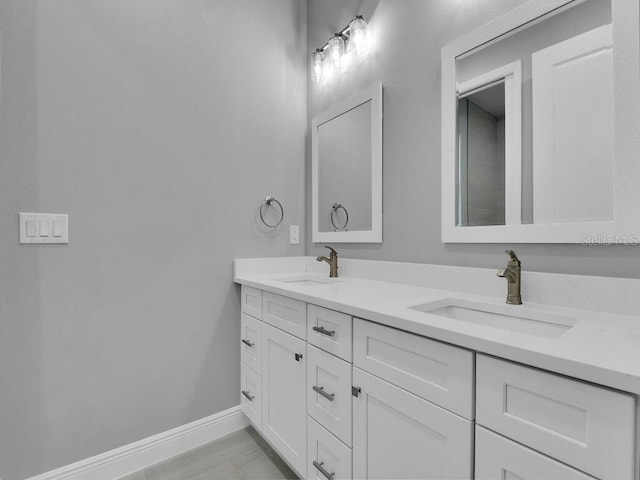 full bath with baseboards, a sink, and double vanity