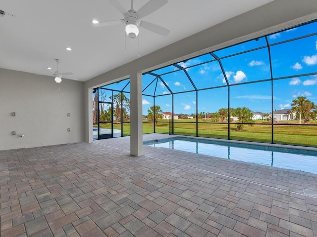 pool featuring ceiling fan, glass enclosure, a patio area, and a yard