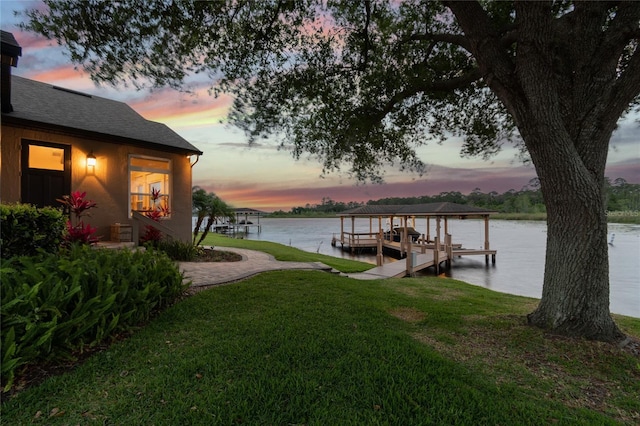 view of dock with a yard, a water view, and boat lift