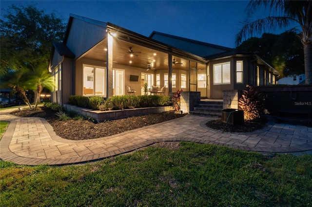 rear view of property with stucco siding and ceiling fan