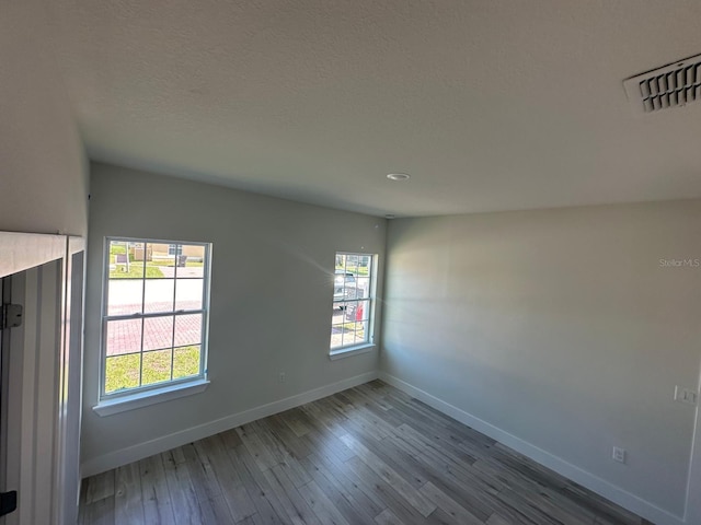 unfurnished room featuring recessed lighting, wood finished floors, visible vents, and baseboards