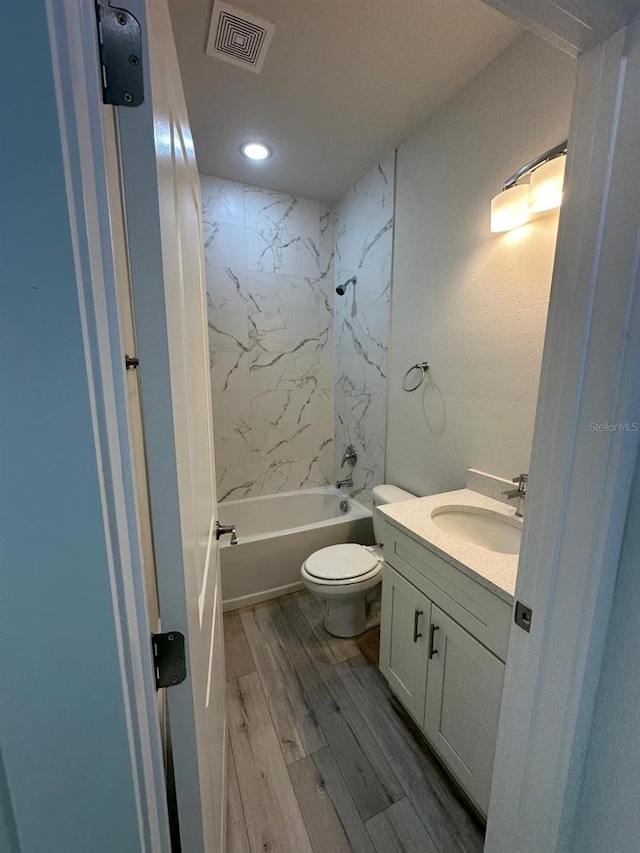 bathroom with wood finished floors, vanity, shower / washtub combination, toilet, and visible vents
