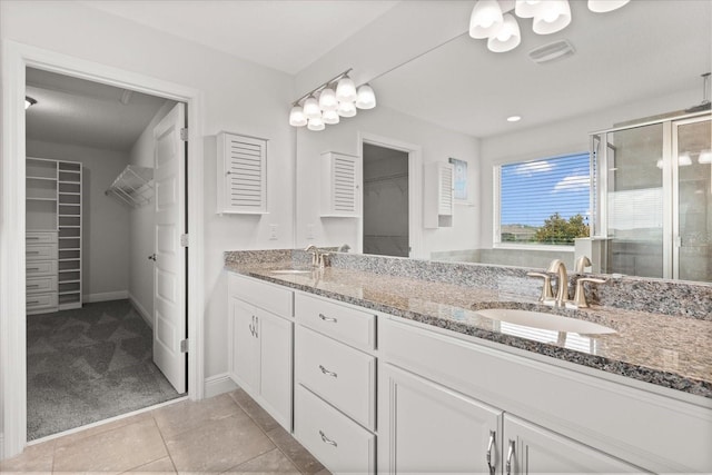 16124 Azure Key St, Winter Garden, FL 34787 - full bathroom with a walk in closet, double vanity, a stall shower, baseboards, and tile patterned floors