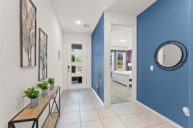 interior space featuring visible vents, baseboards, light tile patterned floors, and light colored carpet