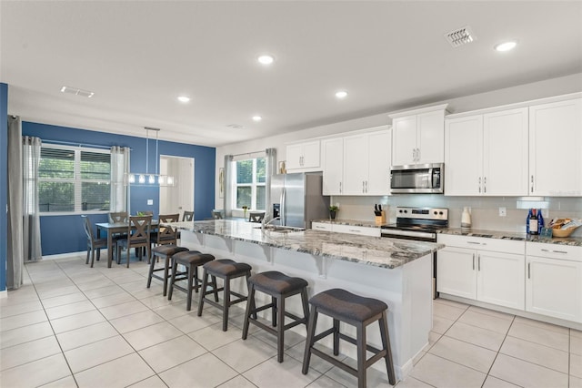kitchen featuring stainless steel appliances, recessed lighting, and an island with sink