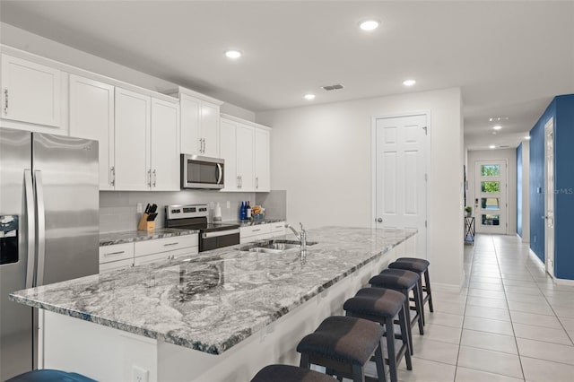 kitchen with light tile patterned flooring, a kitchen bar, recessed lighting, a sink, and appliances with stainless steel finishes