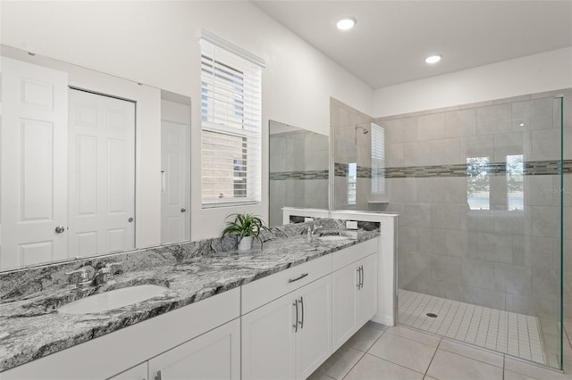 bathroom with double vanity, a sink, walk in shower, and tile patterned floors