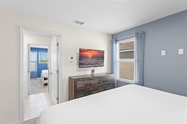 bedroom featuring visible vents, carpet, tile patterned floors, and multiple windows