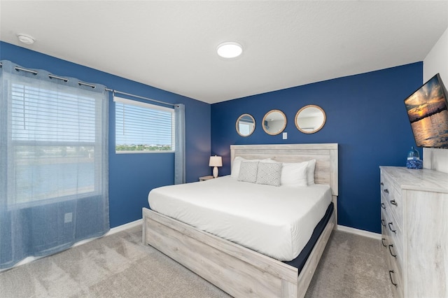 bedroom with baseboards and light carpet