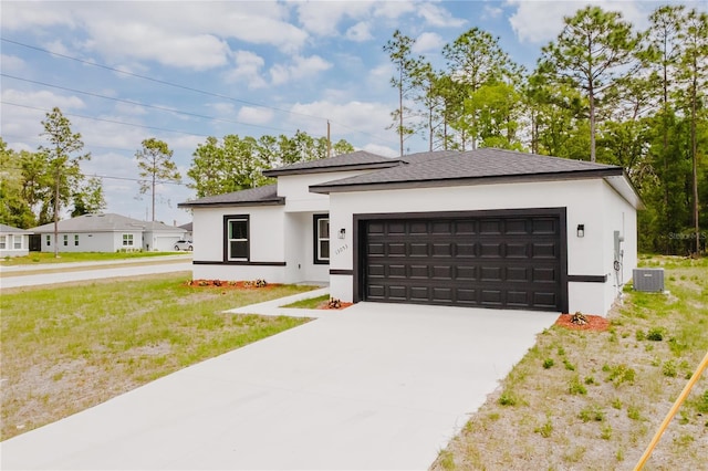 prairie-style house featuring stucco siding, a shingled roof, central AC unit, concrete driveway, and an attached garage