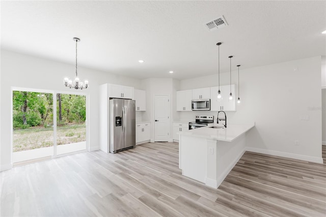 kitchen featuring light wood-style flooring, appliances with stainless steel finishes, visible vents, baseboards, and a peninsula