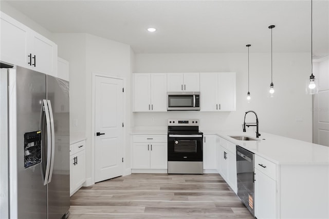 kitchen with white cabinets, light wood-style flooring, a sink, appliances with stainless steel finishes, and a peninsula