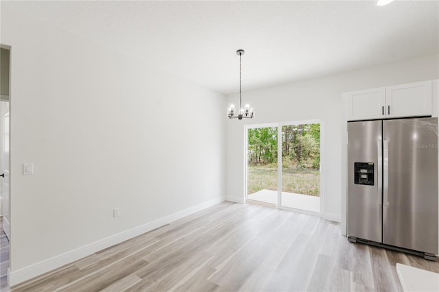 unfurnished dining area featuring baseboards, light wood finished floors, and a notable chandelier