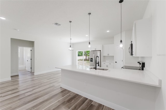 kitchen with light wood finished floors, a sink, stainless steel appliances, a peninsula, and white cabinets