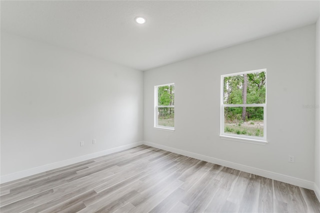 unfurnished room featuring recessed lighting, light wood finished floors, and baseboards