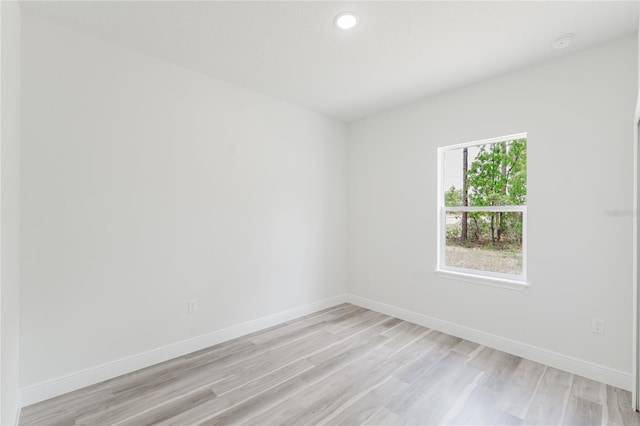 empty room featuring light wood finished floors, recessed lighting, and baseboards