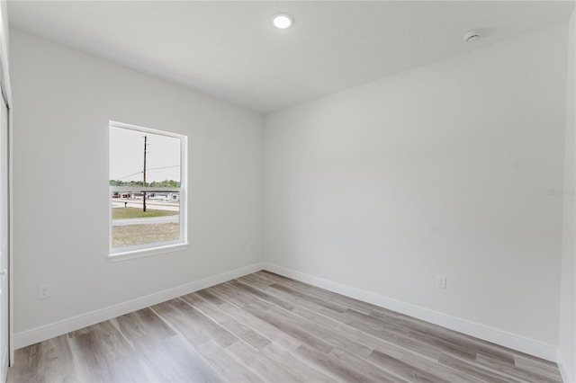 empty room featuring baseboards, light wood-type flooring, and recessed lighting