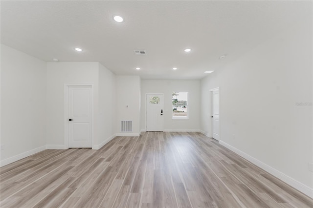 empty room featuring light wood-style floors, recessed lighting, visible vents, and baseboards