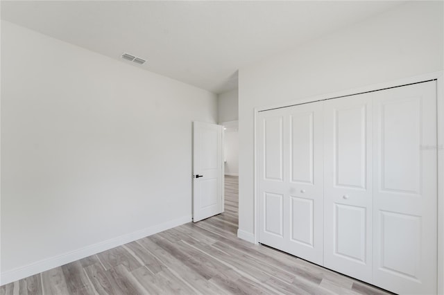 unfurnished bedroom featuring baseboards, visible vents, light wood-type flooring, and a closet