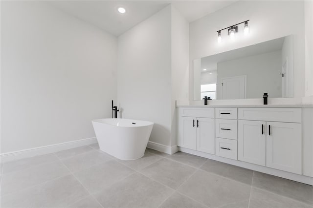 bathroom featuring a sink, double vanity, baseboards, tile patterned floors, and a freestanding bath